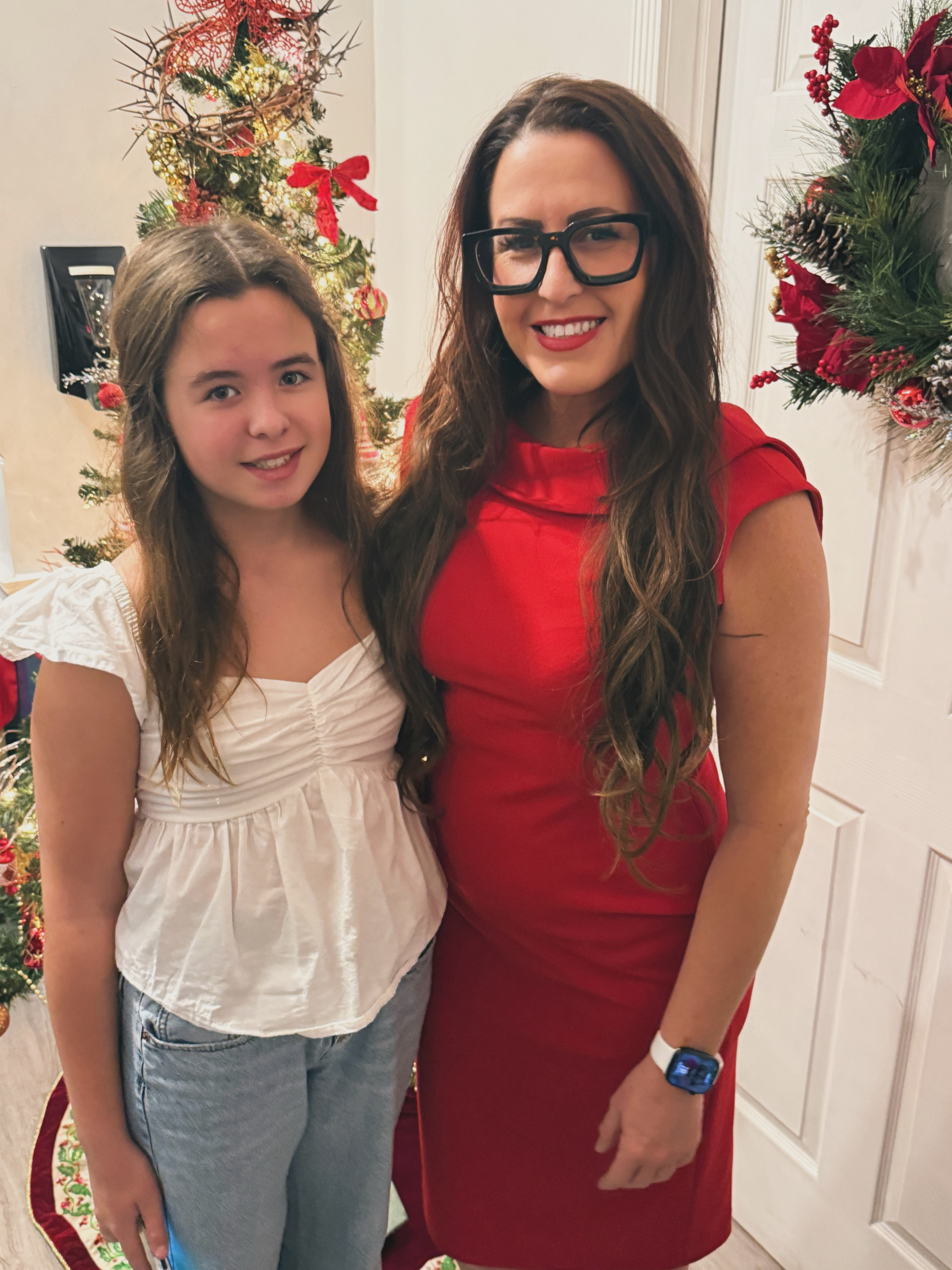 Kate Baldwin and her daughter Olivia standing together in front of a Christmas tree, Kate wearing a red dress